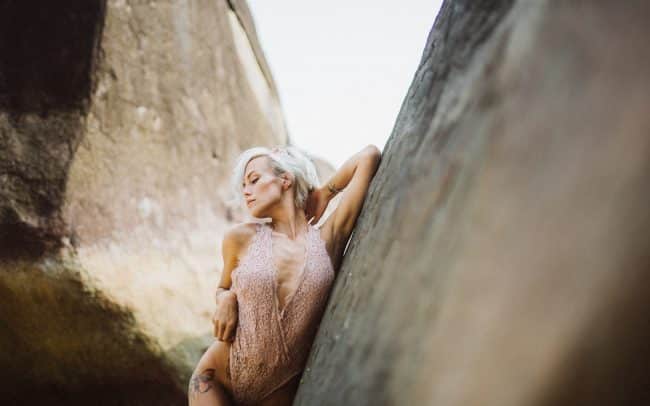 erotische Frau in Spitzenbody lehnt an einem Felsen am Meer