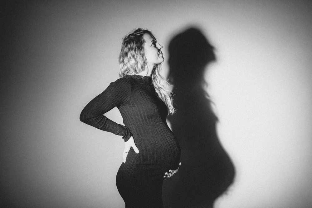 Schwangerschaftsfotografie im Studio blonde Frau im schwarzen Kleid