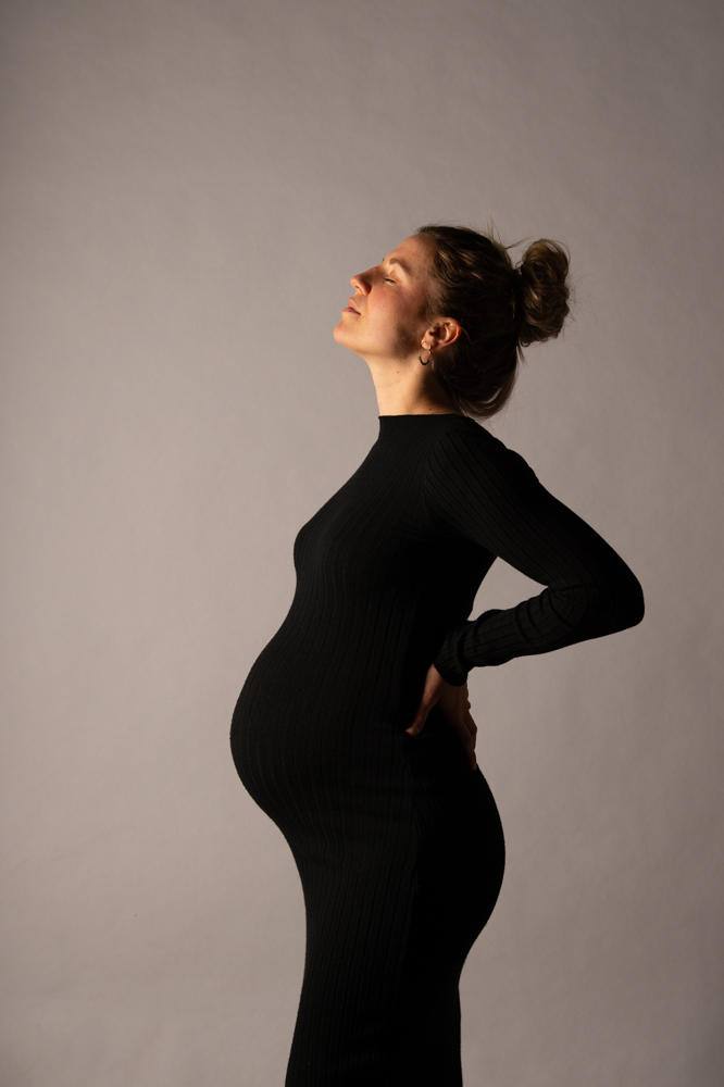 Schwangerschaftsfotografie im Studio blonde Frau im schwarzen Kleid